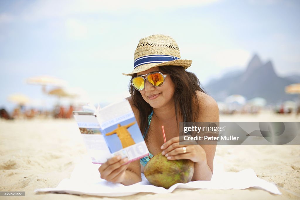 Mature woman reading tourist guide, Ipanema beach, Rio De Janeiro, Brazil