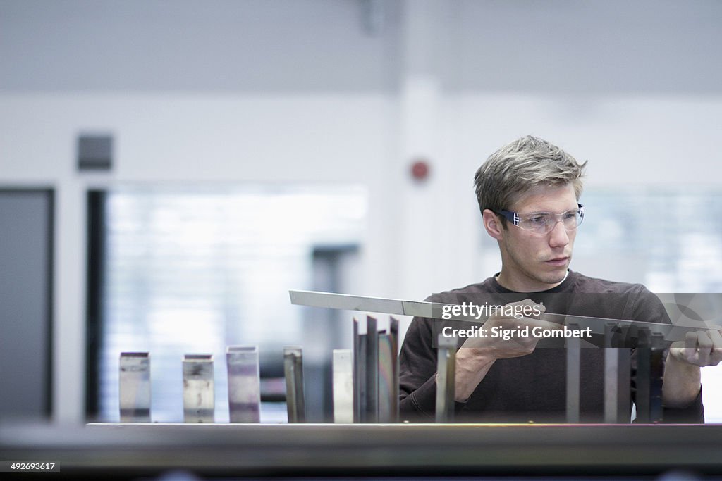 Mid adult male technician checking quality of products in engineering plant