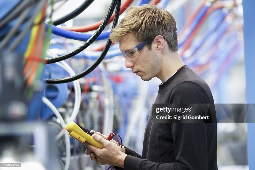 Mid adult male technician testing cables in engineering plant