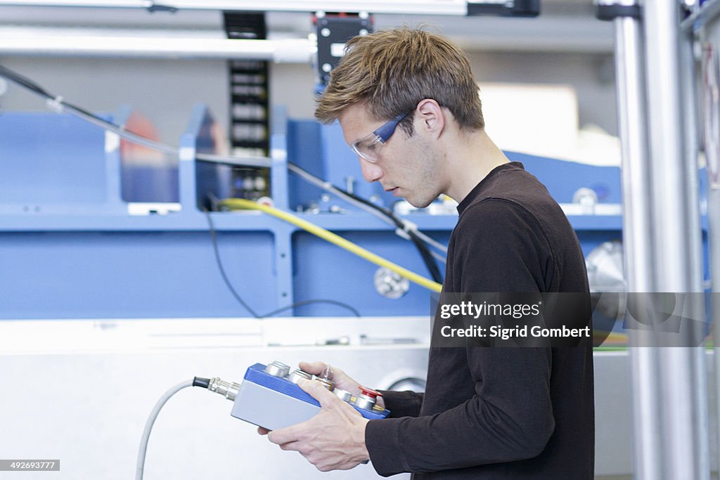 Mid adult male technician monitoring machines in engineering plant