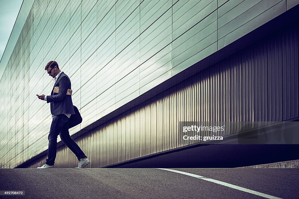 Young casual businessman using smartphone in the urban environment