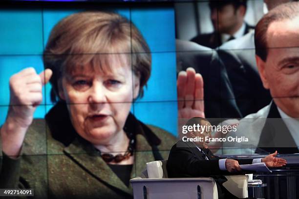 Former Italian Prime Minister Silvio Berlusconi attends the 'Porta A Porta' TV show at the RAI TV studios while a portrait of German Chancellor...