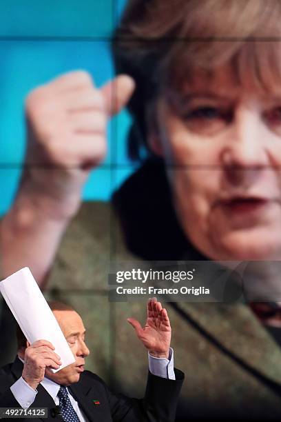 Former Italian Prime Minister Silvio Berlusconi attends the 'Porta A Porta' TV show at the RAI TV studios while a portrait of German Chancellor...