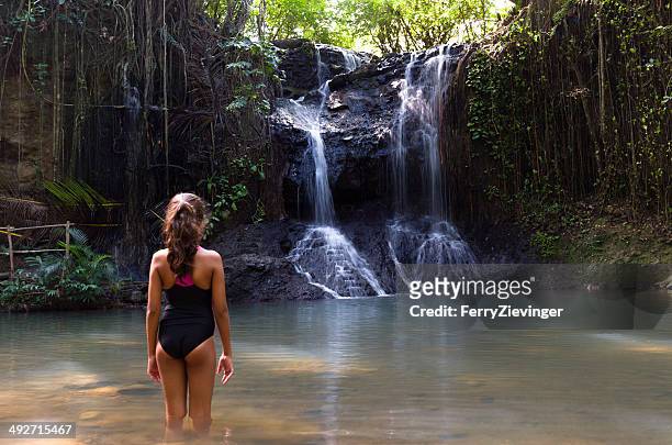 girl standing in lake looking at waterfall, caribbean - tween girl swimsuit stockfoto's en -beelden