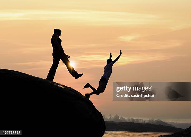 silhouette of a man standing on rock kicking a woman - murder scene 個照片及圖片檔