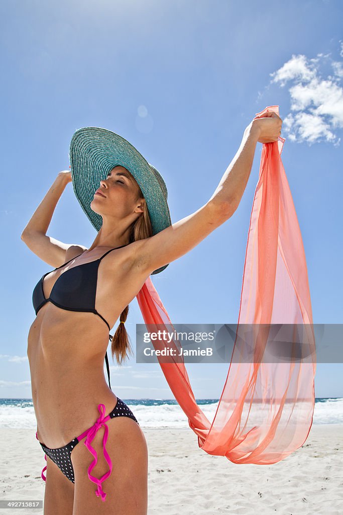 Mujer joven en la playa con una bufanda de seda