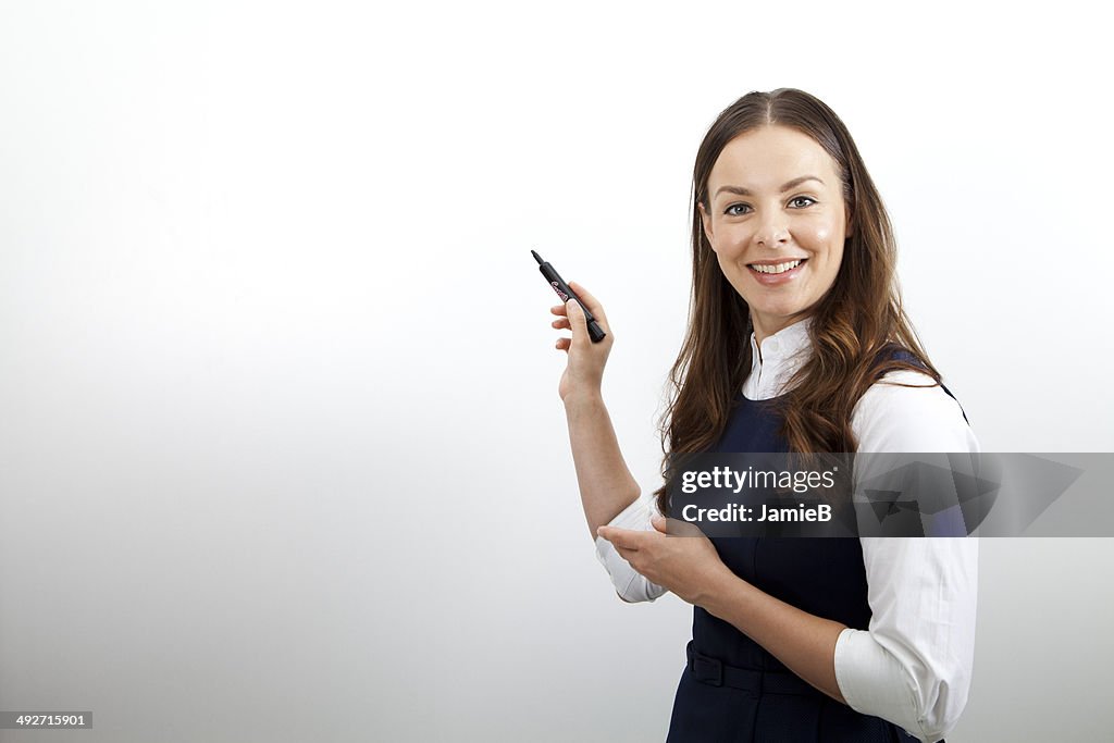Businesswoman standing by whiteboard doing presentation