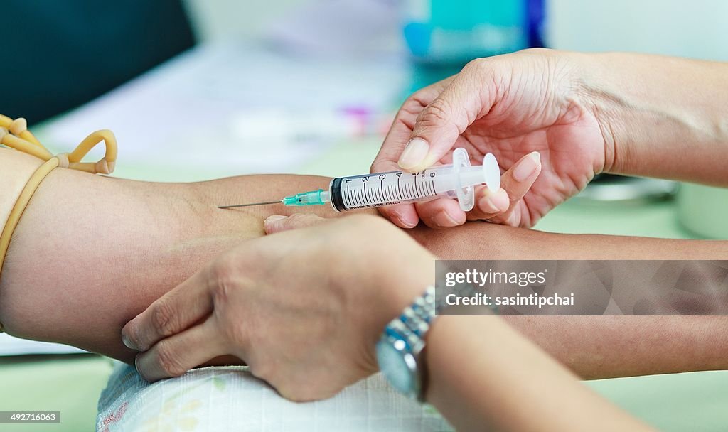 Doctor drawing blood sample from arm for blood test