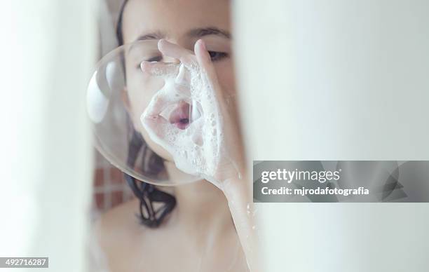 girl standing in shower blowing soap bubbles - kids taking a shower stockfoto's en -beelden