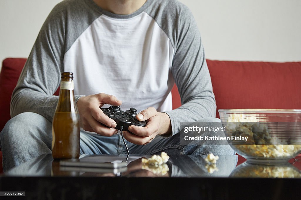 Mid adult man sitting on sofa using computer game control