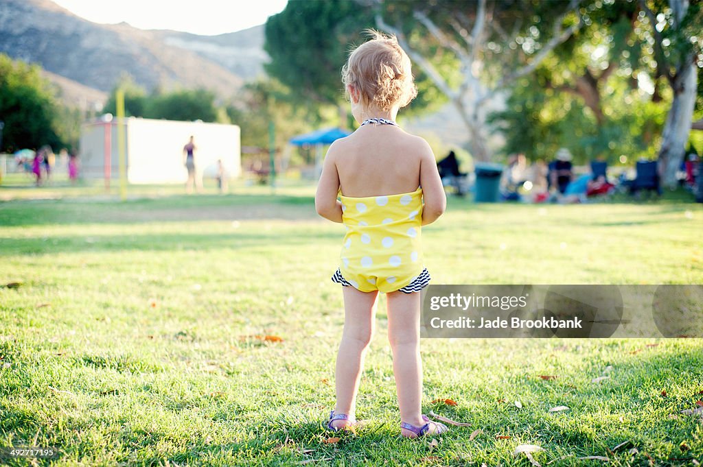 Rear view of female toddler standing in park field