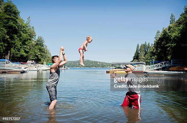 female toddler thrown and caught mid air by young men - lac arrowhead photos et images de collection