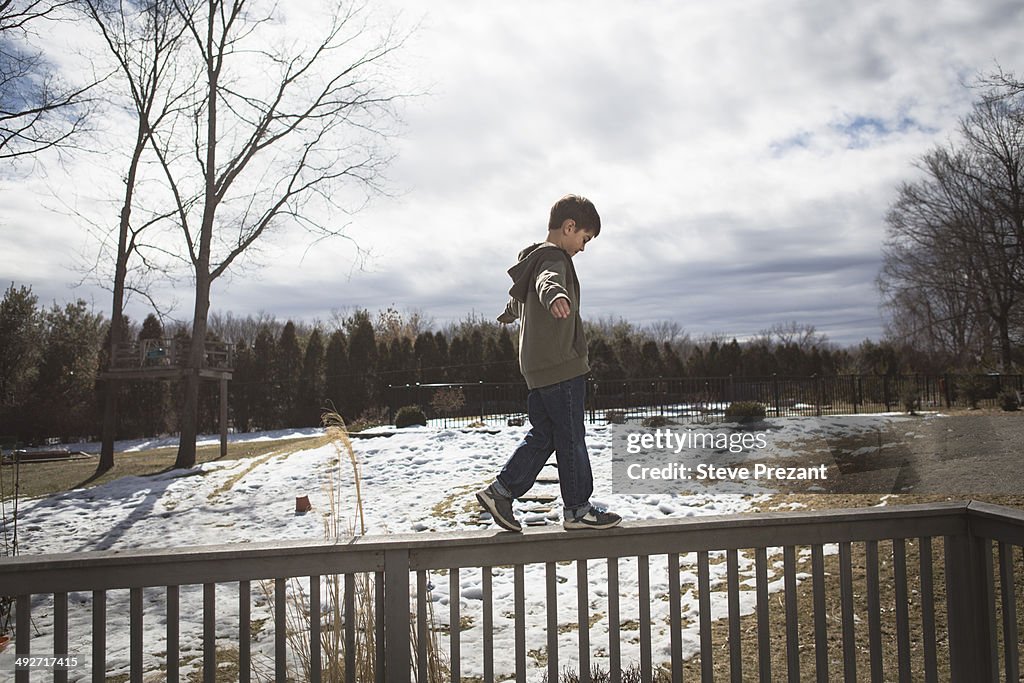 Boy walking along top of fence in park