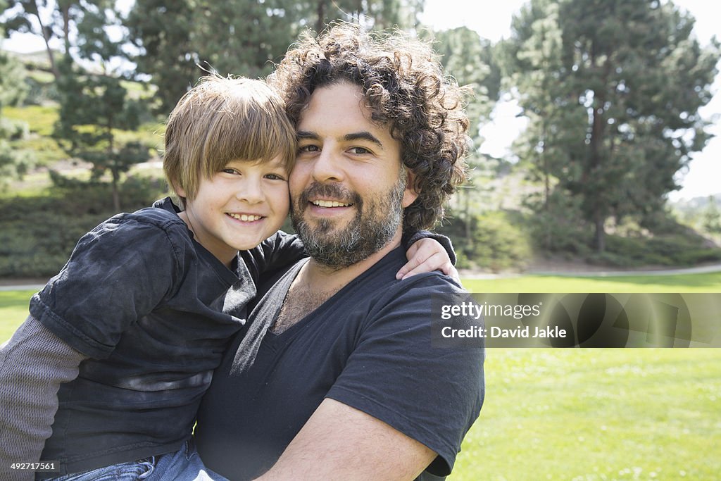 Portrait of proud father and son in park