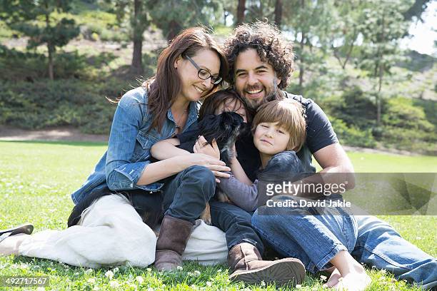 portrait of family with two boys and dog sitting in park - front view portrait of four children sitting on rock stock-fotos und bilder
