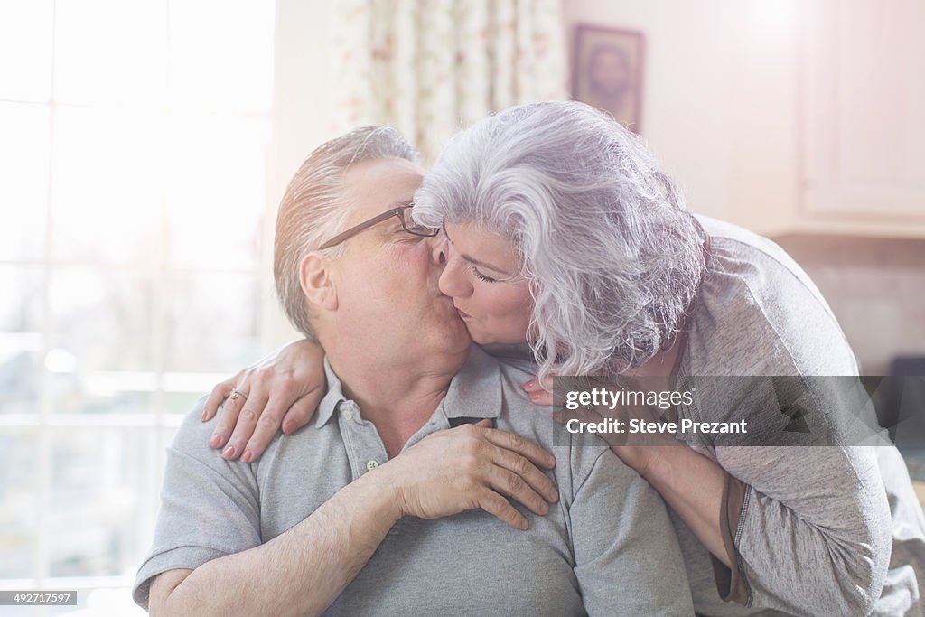 Affectionate mature adult couple kissing at home