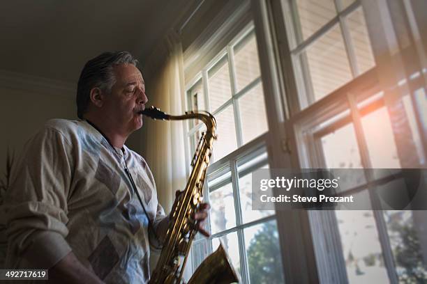 mature man at home playing saxophone - saxophone 個照片及圖片檔