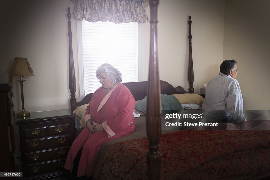 Mature couple sitting on opposite sides of bed