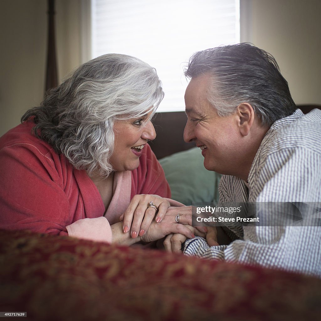 Affectionate mature adult couple lying on bed