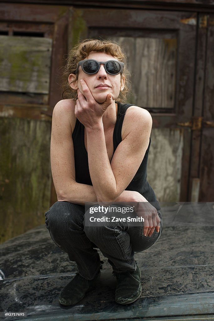 Portrait of woman in sunglasses on car bonnet