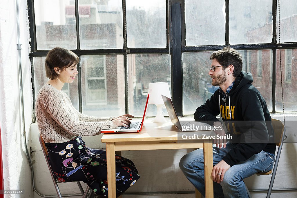 Male and female designers working on laptops in studio