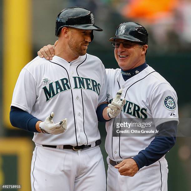John Buck of the Seattle Mariners is greeted by first base coach Andy Van Slyke after singling against the Kansas City Royals at Safeco Field on May...