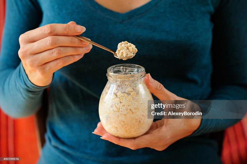 Woman's slender hands holding glass jar overnight oat