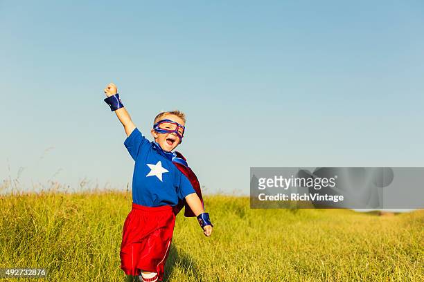 giovane ragazzo vestito come supereroe solleva il braccio - vestito a stelle foto e immagini stock