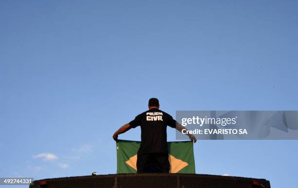 Brazilian civil policeman holds a national flag during a protest at the Ministry Esplanade during a one-day strike in Brasilia, Brazil on May 21,...