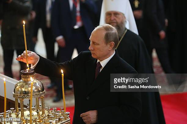 Russian President Vladimir Putin lights a candle while visiting the Dormition Cathedral of Russian Orthodox Church on October 15, 2015 in Astana,...