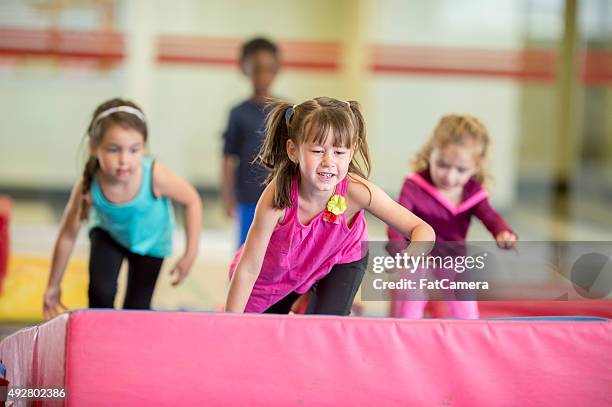 crawling over gymnastics mats - gymnastiek stockfoto's en -beelden