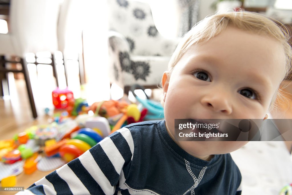 Male toddler taking a selfie with his toys behind