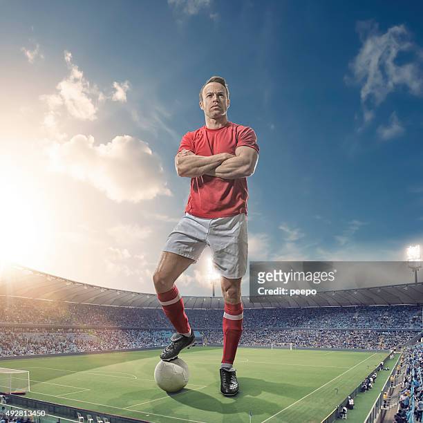 giant footballer standing in floodlit soccer stadium at sunset - football player stock pictures, royalty-free photos & images