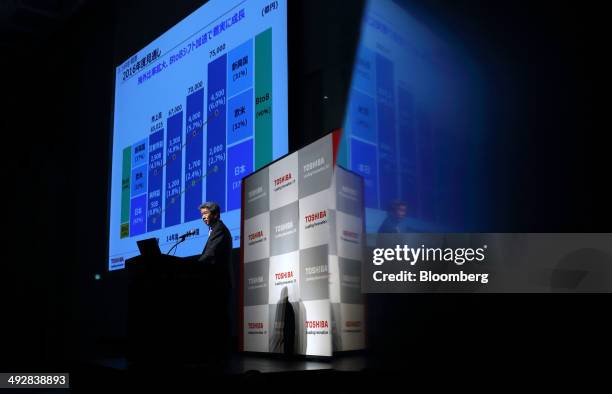 Hisao Tanaka, president and chief executive officer of Toshiba Corp., standing at a podium is reflected on a wall as he speaks during a news...