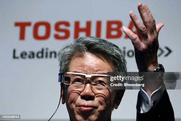 Hisao Tanaka, president and chief executive officer of Toshiba Corp., wears the company's wearable display device as he speaks during a news...