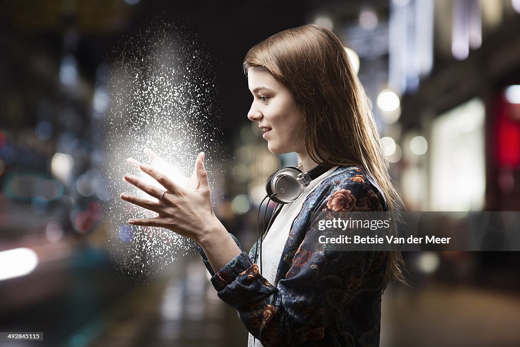 Teenage girl looks at energy source between hands.