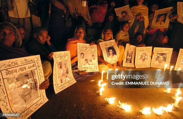 Bhopal gas leak victims hold portraits lost ones during a candle light vigile to the victims of the tragedy to mark the 20th anniversary of the...