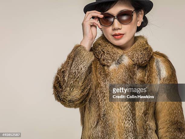 southeast asian woman in fur coat and sunglasses - fur coat stockfoto's en -beelden
