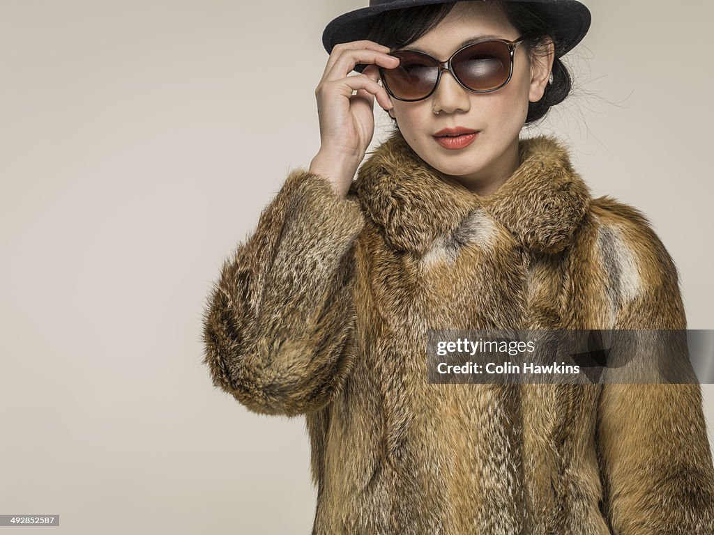 Southeast Asian woman in fur coat and sunglasses