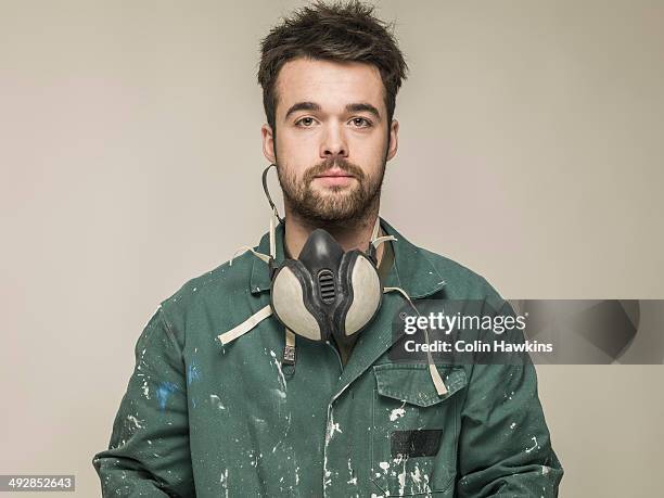 young man wearing safety mask and overalls - protective workwear for manual worker stockfoto's en -beelden