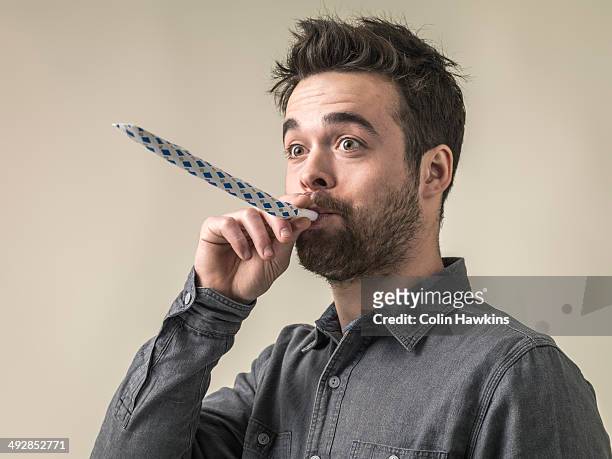 young male blowing party horn - party favor foto e immagini stock