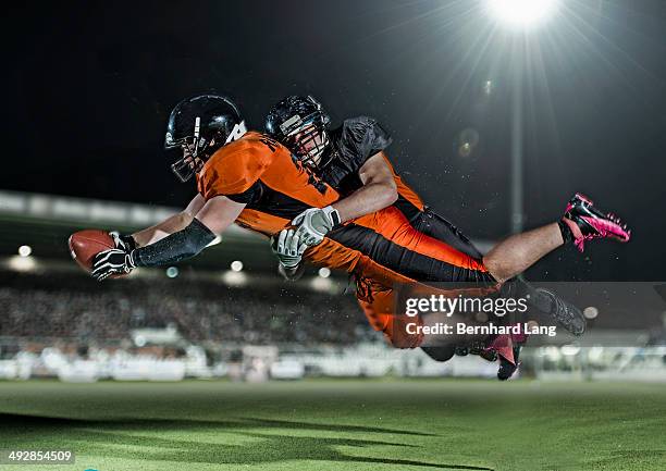 american football player tackling opponent - football spieler stock-fotos und bilder