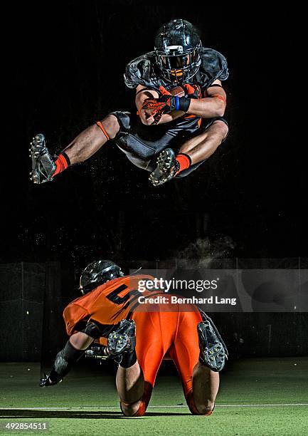 american football player jumping in mid-air - tackle american football positie stockfoto's en -beelden