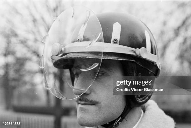Racing driver Graham Hill demonstrating the new rain proof safety helmet, April 16th 1964.