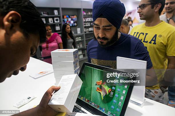 Customer purchases an Apple Inc. IPhone 6s at an iZenica store, operated by Zenica LifestylePvt., during a midnight launch event in New Delhi, India,...