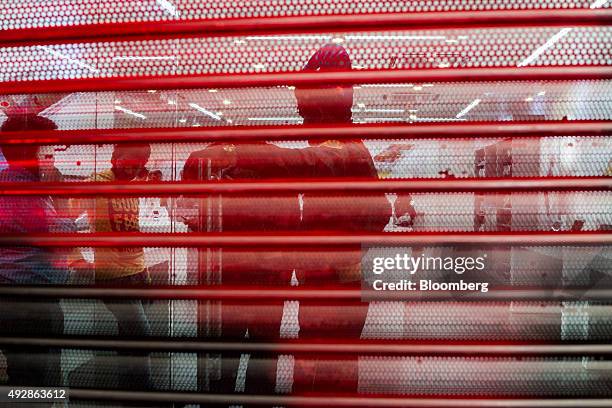 Security guards stand behind the shutters of an iZenica store, operated by Zenica Lifestyle Pvt., prior to a midnight launch event for the Apple Inc....