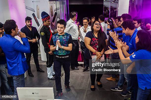 Employees greet the first customers entering an iZenica store, operated by Zenica LifestylePvt., during a midnight launch event for the Apple Inc....