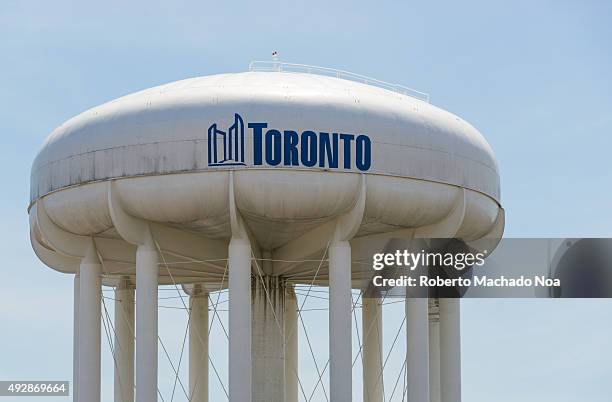 Closeup of overhead water tower in Toronto. The tower has disk-shaped water tanker on the top to store potable water. The tower is white in colour...