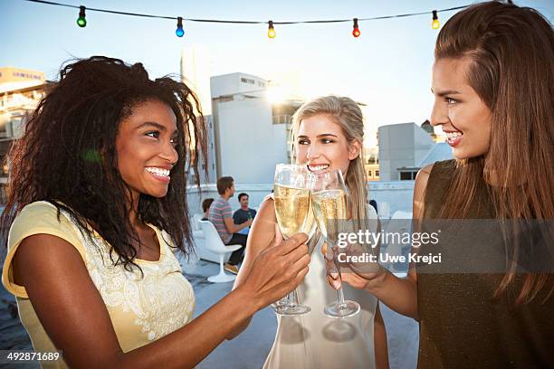 young women celebrating, raising champagne flutes - woman holding champagne stock-fotos und bilder