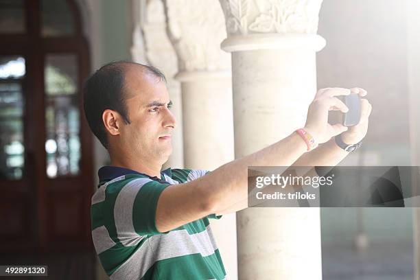 mid adult man taking picture of smart phone - hair loss stock pictures, royalty-free photos & images